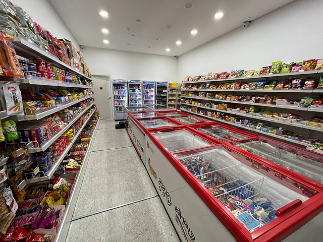 Interior of an unmanned Korean snack shop with red ice cream freezers and no staff at the counter